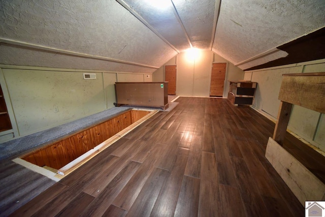 additional living space featuring vaulted ceiling and dark wood-type flooring