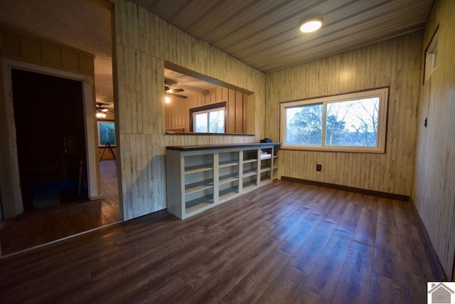 interior space with ceiling fan, dark wood-type flooring, and wooden walls