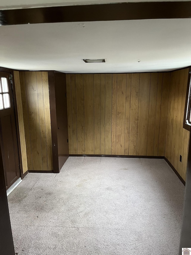 carpeted spare room featuring wooden walls