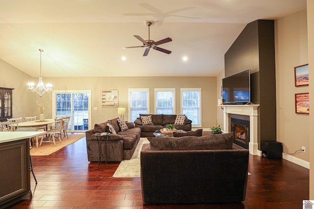 living room featuring ceiling fan with notable chandelier, dark hardwood / wood-style flooring, and vaulted ceiling