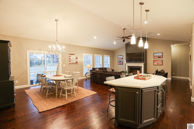 kitchen with a center island, lofted ceiling, ceiling fan with notable chandelier, decorative light fixtures, and dark hardwood / wood-style flooring