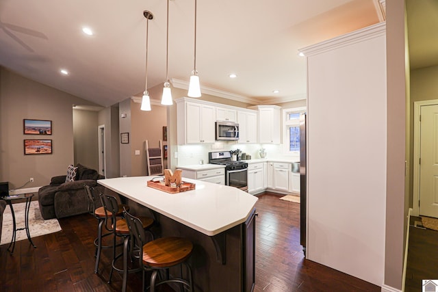 kitchen featuring white cabinetry, hanging light fixtures, tasteful backsplash, a kitchen breakfast bar, and appliances with stainless steel finishes