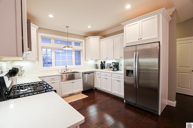 kitchen with appliances with stainless steel finishes, sink, dark hardwood / wood-style floors, white cabinetry, and hanging light fixtures