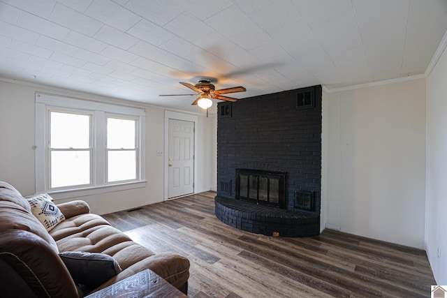 living room with a fireplace, wood-type flooring, ceiling fan, and crown molding