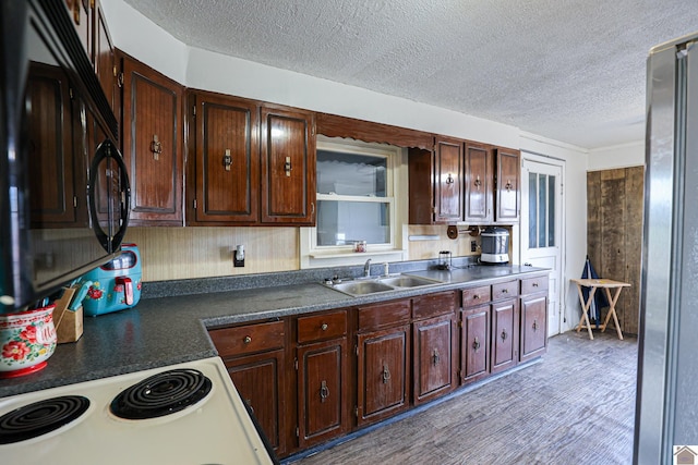 kitchen with stove, sink, stainless steel fridge, a textured ceiling, and dark brown cabinetry