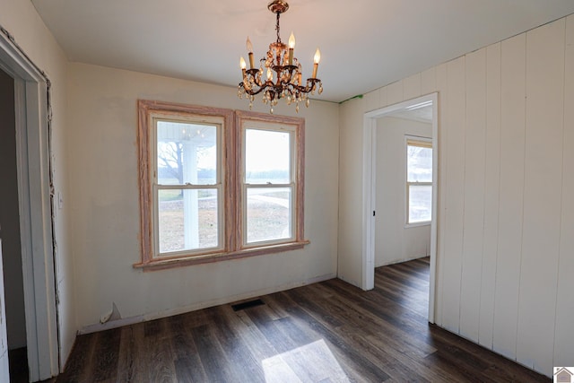 unfurnished dining area with dark hardwood / wood-style flooring, an inviting chandelier, and a healthy amount of sunlight