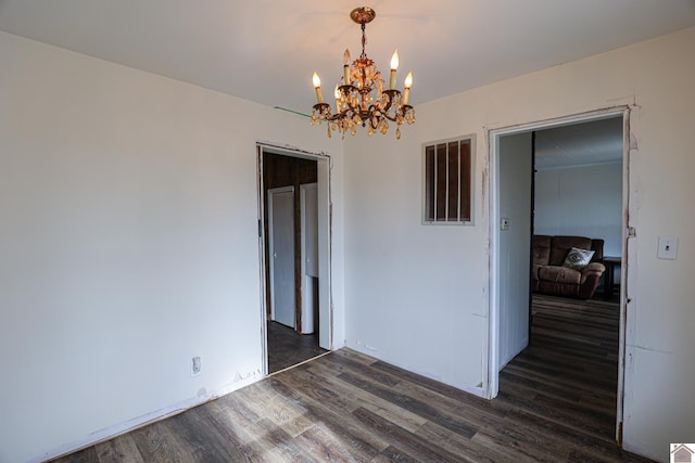 unfurnished room with a notable chandelier and dark hardwood / wood-style floors