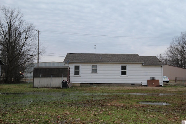 rear view of property with a yard and central air condition unit