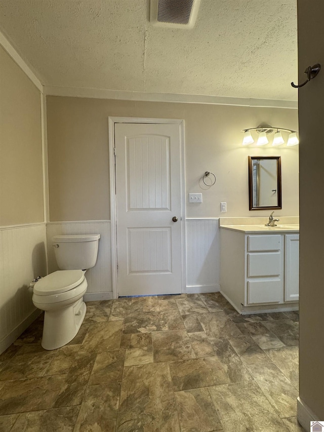 bathroom featuring vanity, toilet, and a textured ceiling