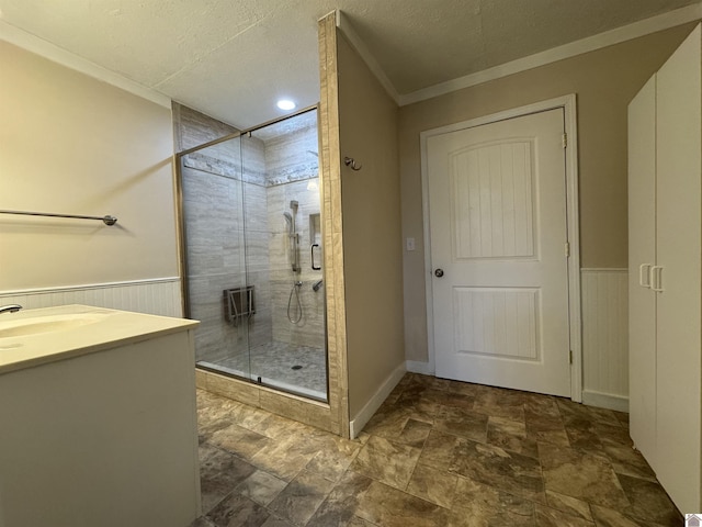 bathroom with vanity, a textured ceiling, a shower with door, and crown molding