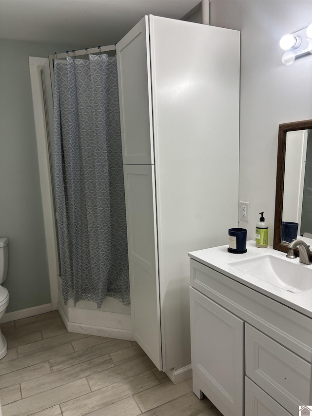 bathroom featuring toilet, a shower with shower curtain, and vanity