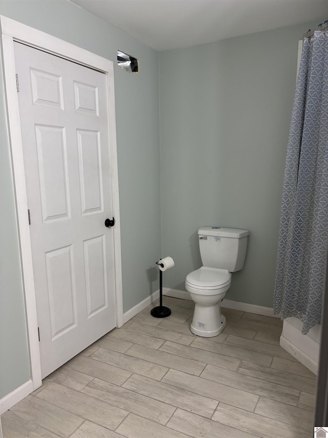 bathroom featuring a shower with shower curtain, hardwood / wood-style floors, and toilet