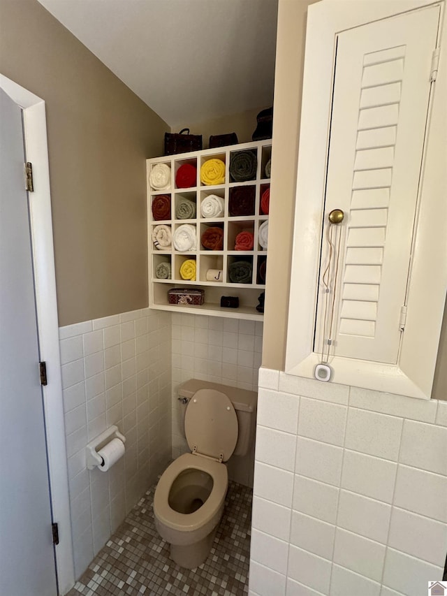 bathroom with tile patterned flooring, toilet, and tile walls