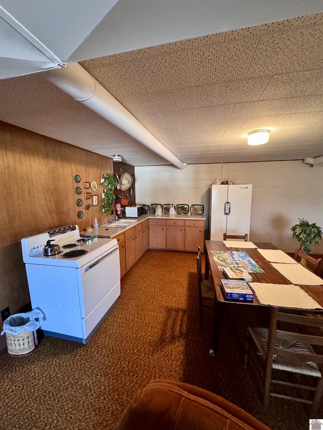 kitchen with light brown cabinetry, white appliances, and wooden walls