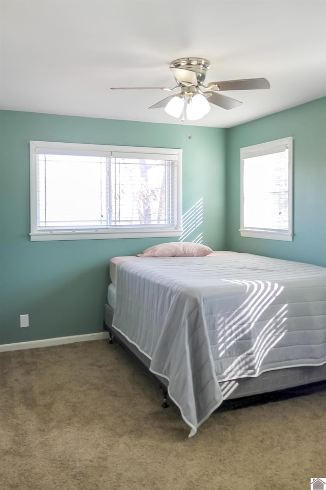 carpeted bedroom featuring multiple windows and ceiling fan