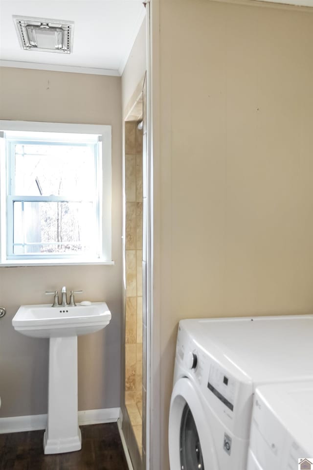 laundry room with dark hardwood / wood-style floors, ornamental molding, sink, and separate washer and dryer