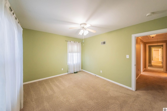 spare room with ceiling fan and light carpet