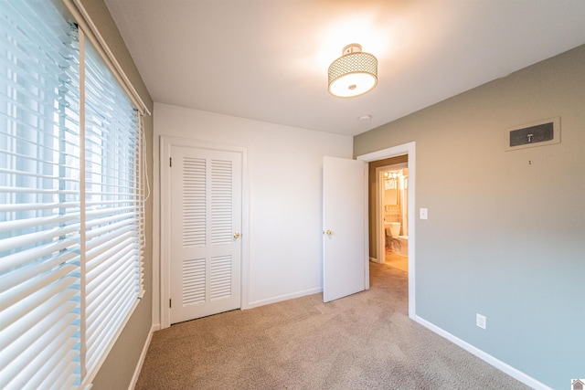 unfurnished bedroom with a closet and light colored carpet