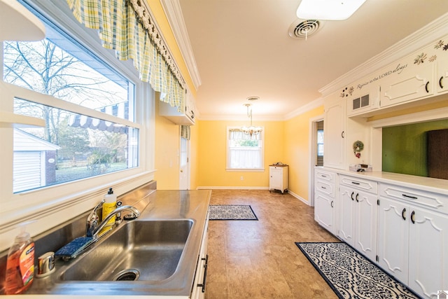 kitchen with crown molding, sink, white cabinets, and pendant lighting