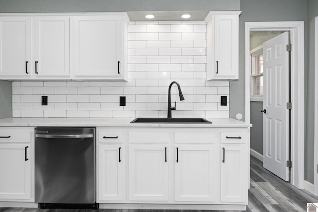 kitchen featuring decorative backsplash, stainless steel dishwasher, sink, light hardwood / wood-style flooring, and white cabinets