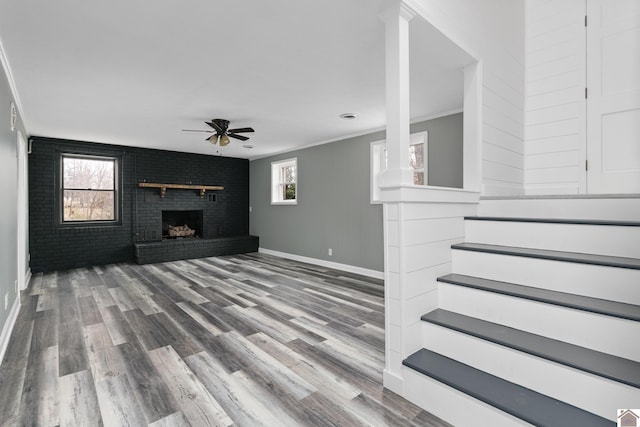 unfurnished living room featuring a brick fireplace, ceiling fan, plenty of natural light, and ornamental molding