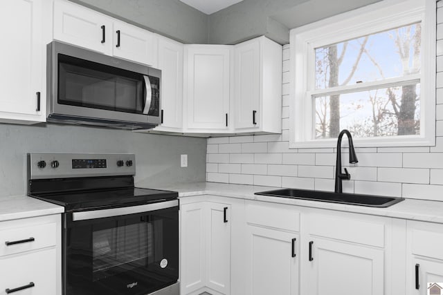 kitchen featuring white cabinetry, sink, light stone counters, and appliances with stainless steel finishes