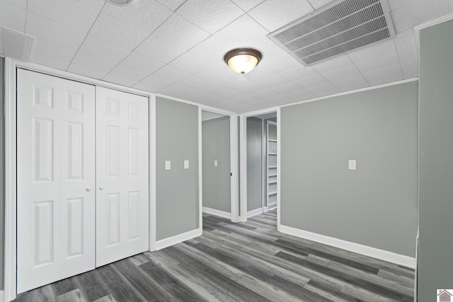 interior space featuring a closet, dark wood-type flooring, and ornamental molding