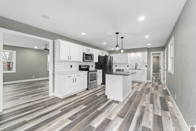 kitchen with white cabinets, decorative light fixtures, sink, and appliances with stainless steel finishes