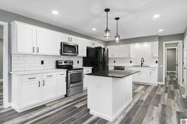 kitchen with appliances with stainless steel finishes, sink, white cabinets, a center island, and dark hardwood / wood-style floors