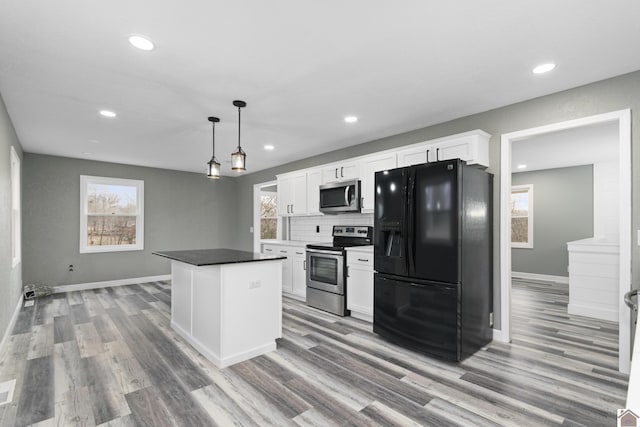 kitchen featuring pendant lighting, white cabinets, decorative backsplash, a kitchen island, and stainless steel appliances