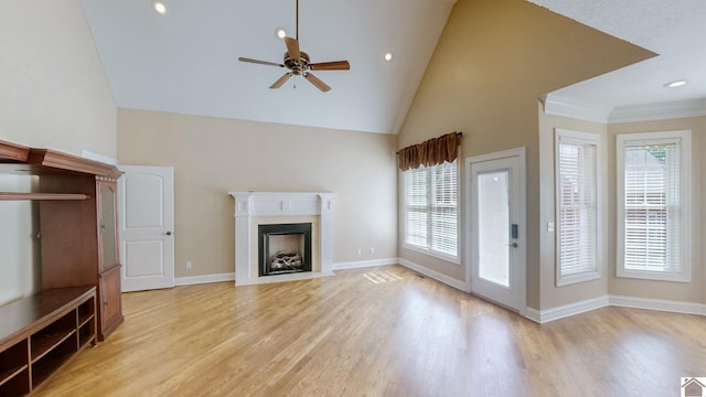 unfurnished living room with ceiling fan, light wood-type flooring, ornamental molding, and high vaulted ceiling