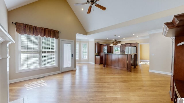 kitchen with stainless steel refrigerator, a center island, hanging light fixtures, ceiling fan with notable chandelier, and light wood-type flooring