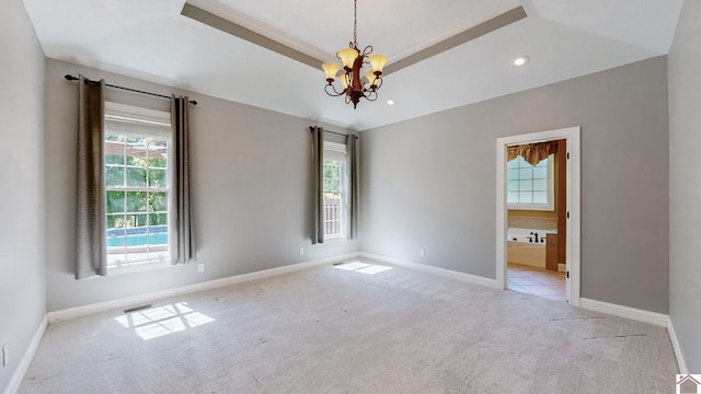 unfurnished room with a raised ceiling, light colored carpet, and a chandelier