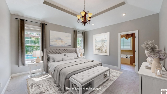 carpeted bedroom featuring a chandelier, a raised ceiling, ensuite bath, and ornamental molding