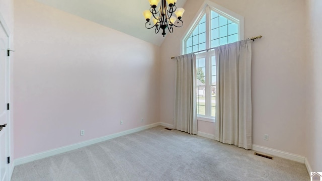 carpeted empty room with a healthy amount of sunlight, lofted ceiling, and an inviting chandelier