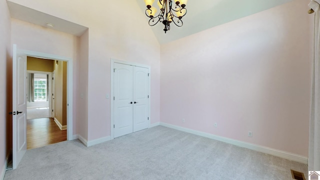 interior space featuring a closet, light colored carpet, a chandelier, and high vaulted ceiling