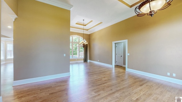 interior space with light wood-type flooring, ornamental molding, a high ceiling, and an inviting chandelier