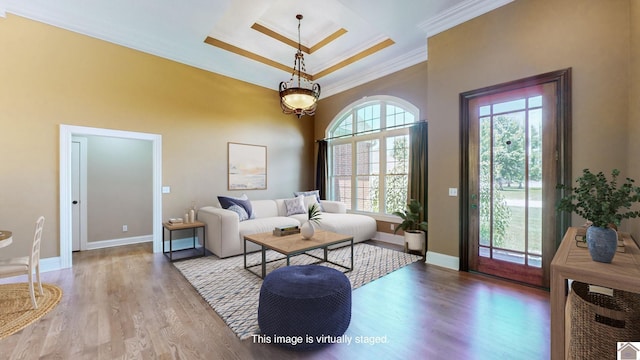 living room featuring a towering ceiling, light wood-type flooring, and crown molding