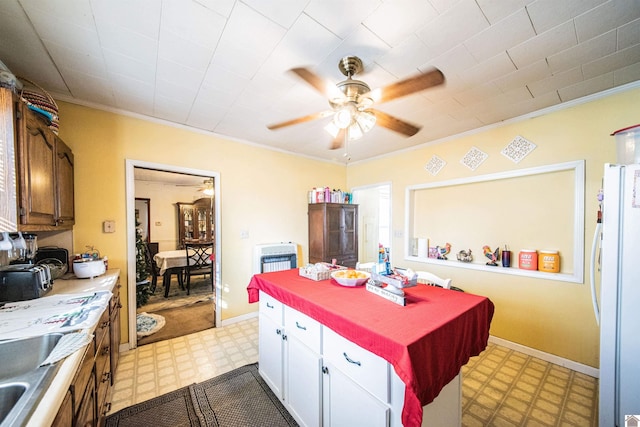 kitchen with a center island, crown molding, ceiling fan, white fridge, and white cabinetry