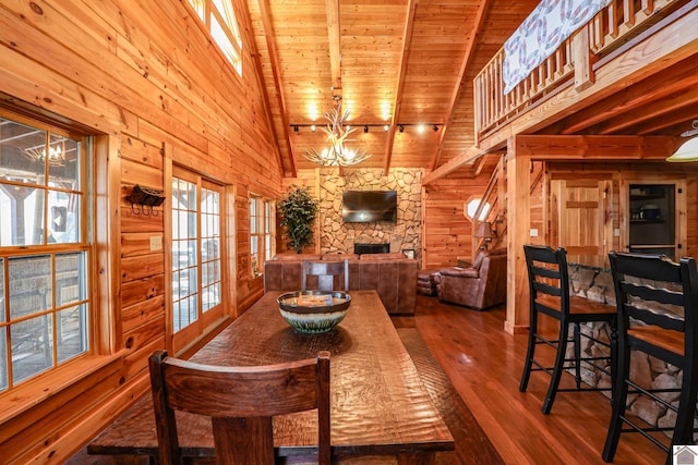 dining area with beam ceiling, hardwood / wood-style flooring, wood walls, and wood ceiling