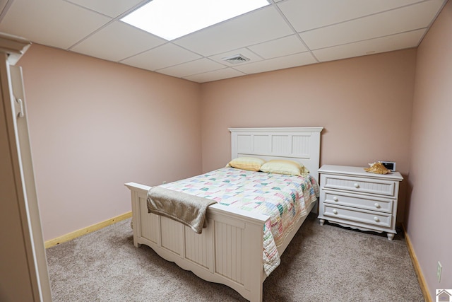 carpeted bedroom featuring a drop ceiling