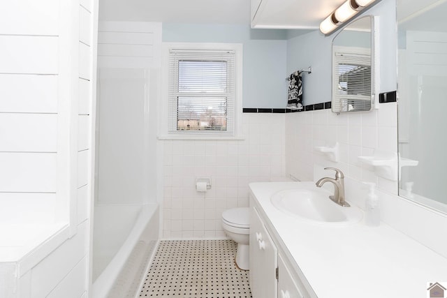 bathroom featuring vanity, toilet, and tile walls