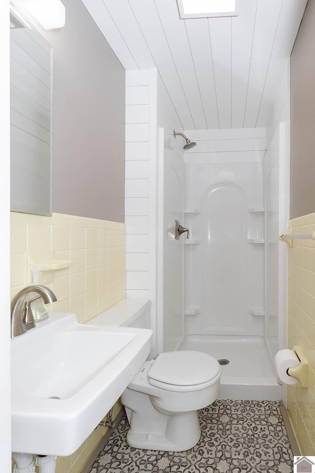 bathroom featuring tile patterned floors, walk in shower, sink, tile walls, and toilet