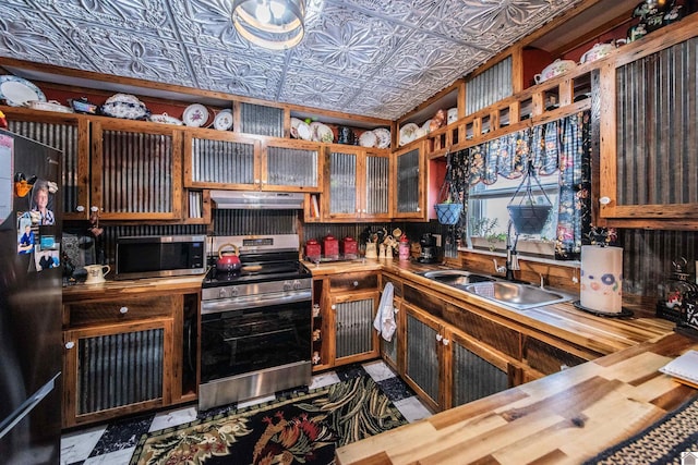 kitchen with wood counters, sink, stainless steel appliances, and extractor fan