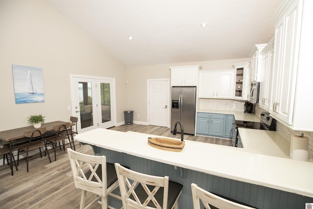 kitchen featuring kitchen peninsula, appliances with stainless steel finishes, tasteful backsplash, and white cabinetry