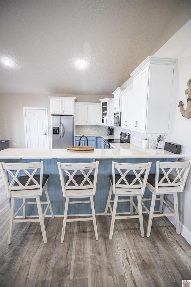 kitchen with a breakfast bar, stainless steel appliances, and kitchen peninsula