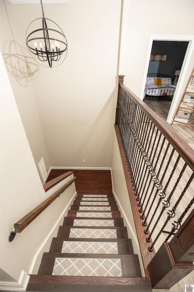 stairs featuring hardwood / wood-style floors and an inviting chandelier