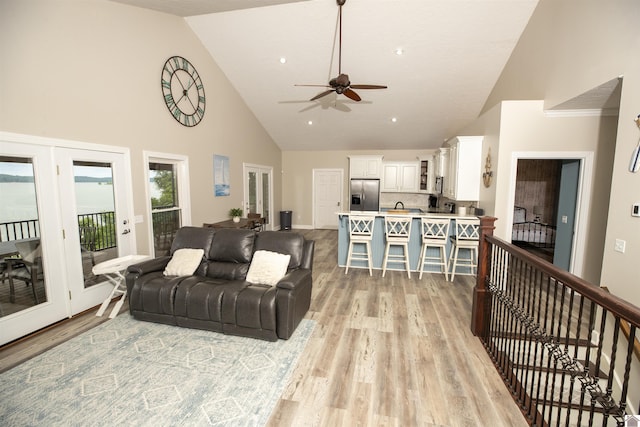 living room with ceiling fan, light wood-type flooring, and high vaulted ceiling