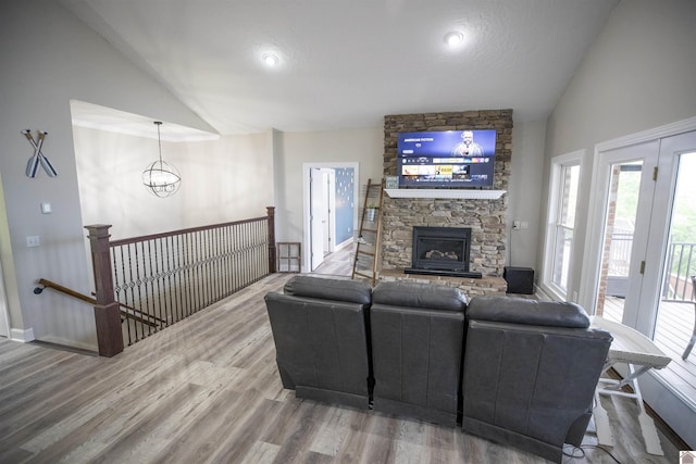 living room with a fireplace, hardwood / wood-style floors, vaulted ceiling, and an inviting chandelier