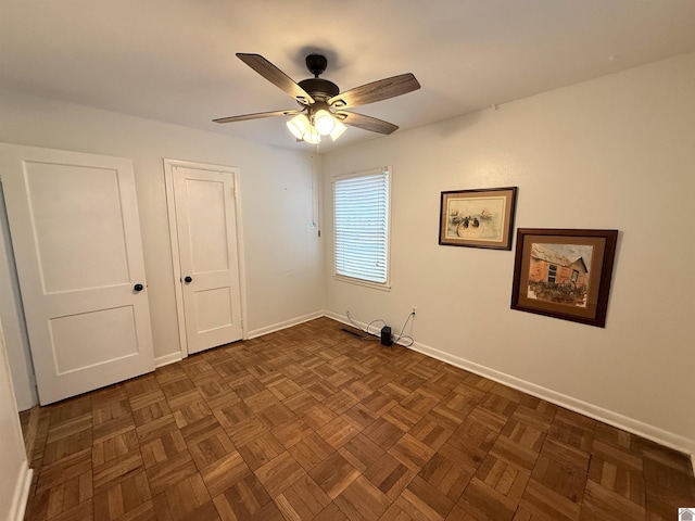 spare room featuring dark parquet flooring and ceiling fan